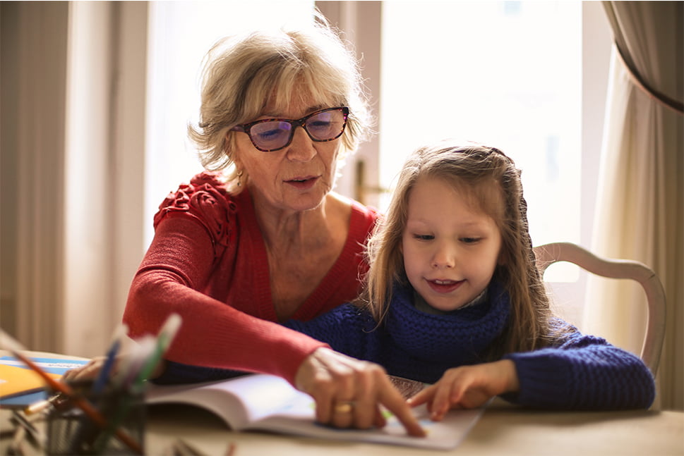 Sød bedstemor underviser pige, hjælper med lektier